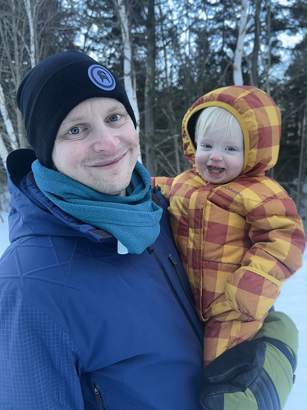 Brian hold his son with snow
