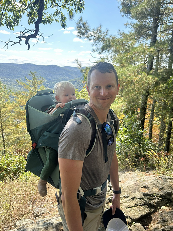 Brian with his son in a hiking kid backpack on a hiking trail